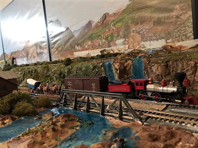 old west town model railroad with a steam engine going over a bridge